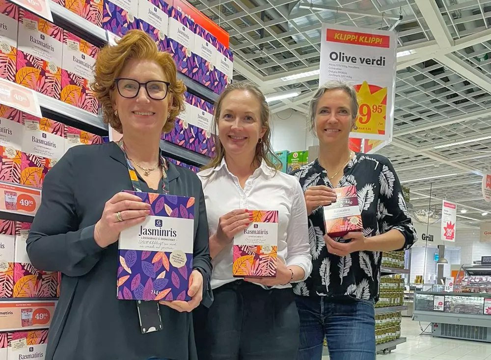 Tre personer står i en matbutik och håller upp Garants nya risförpackningar med SRP-certifiering.