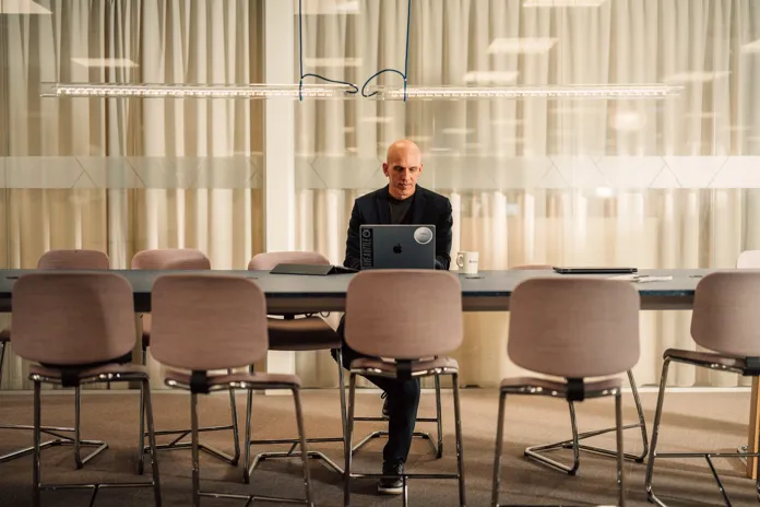 En manlig kollega sitter vid ett stort bord och jobbar på sin dator