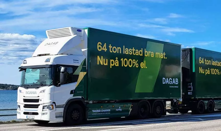 Ellastbil åker på en väg under blå himmel.